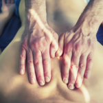 Massage therapist performing Reiki-infused massage with hands on client’s back, offering energy healing and relaxation in Olympia WA