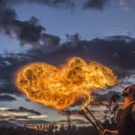 Man blowing onto a torch with flame erupting, representing the power of breathing exercises, energy activation, and breathwork practices