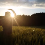 Man performing Qi Gong movements outdoors in a grassy field, symbolizing energy flow, balance, and mindful movement