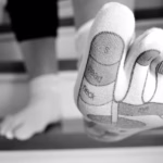 Person wearing sock with foot reflexology map printed on the sole, showing pressure points for massage therapy and holistic healing
