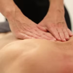 Massage therapist’s hands on a client’s back, representing different types of massage therapy techniques and hands-on healing