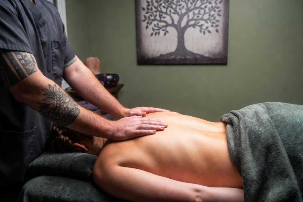 Massage therapist providing a relaxing restorative back massage in a calm clinical treatment room